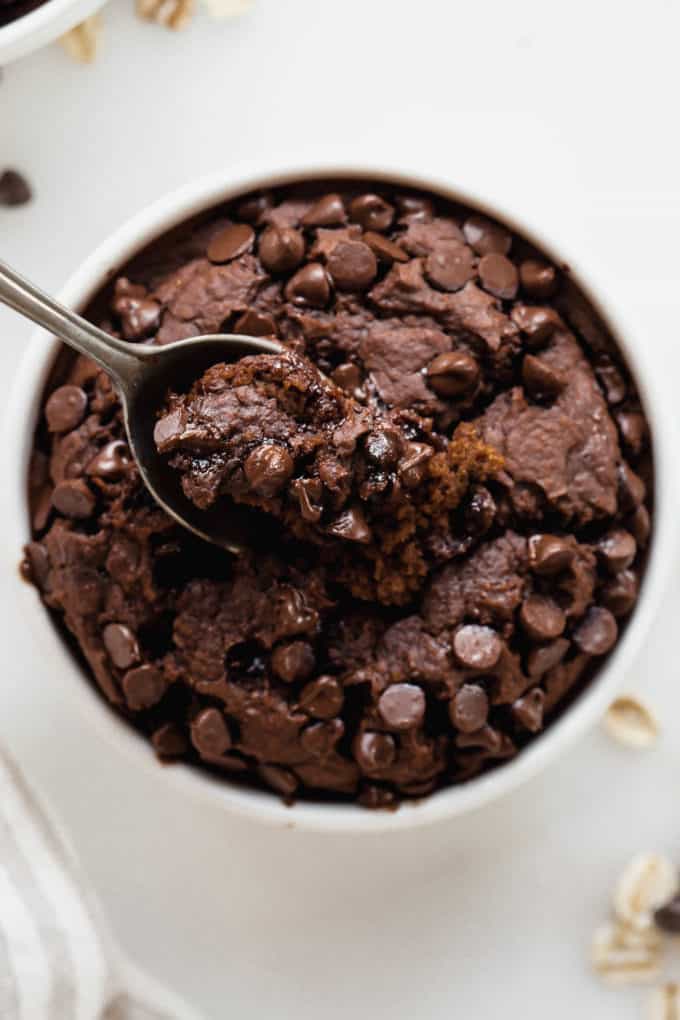 A spoon scooping up chocolate baked oats out of a ramekin