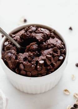 A white ramekin with chocolate baked oats in it topped with chocolate chips