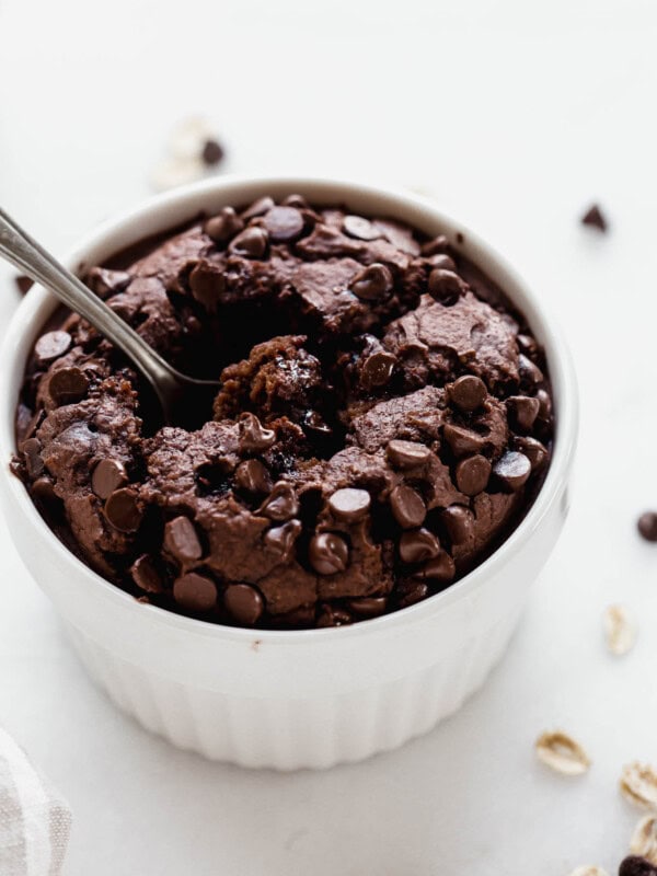 A white ramekin with chocolate baked oats in it topped with chocolate chips