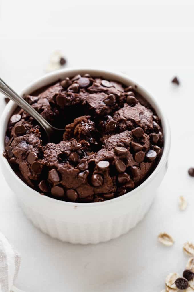 A white ramekin with chocolate baked oats in it topped with chocolate chips