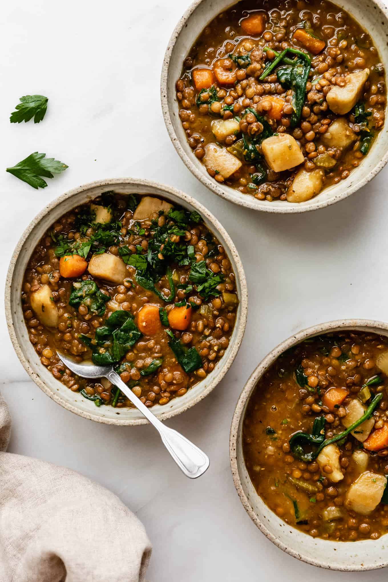 three bowls of lentil stew with parsley on top