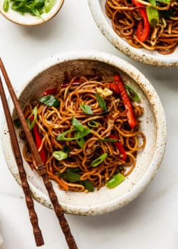 A bowl of vegan chow mein with chopsticks on top