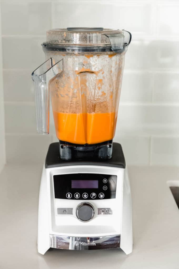 A blender with blended orange juice and ginger juice in it
