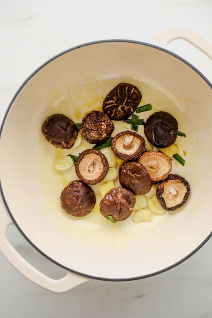 Dried shitake mushrooms, garlic, ginger and green onions in a white pot