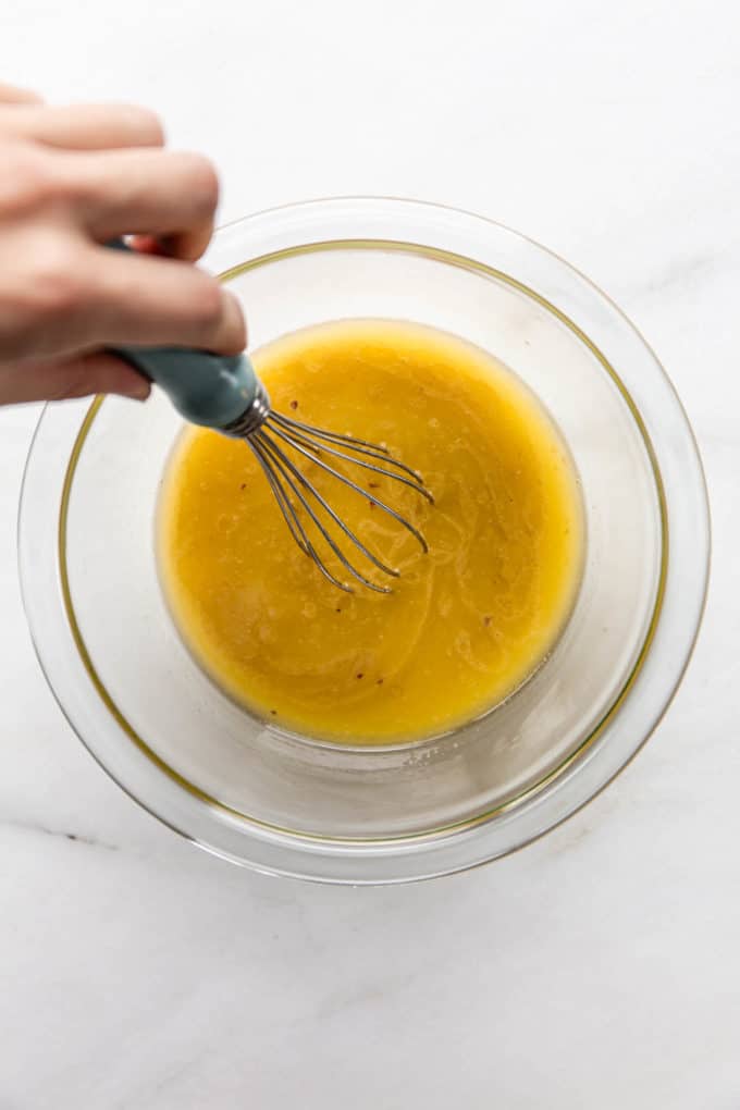 a hand using a whisk to whisk a bowl of vegan butter