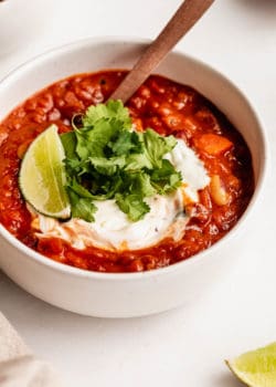 vegan chili topped with cilantro and lime in a white bowl