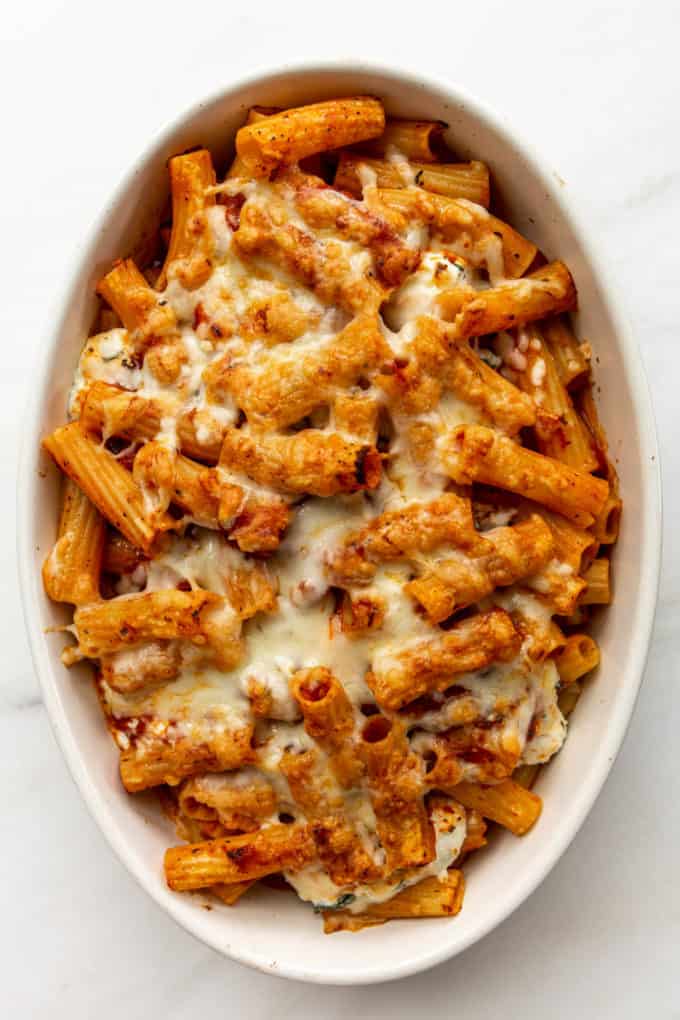 Baked ziti topped with melted cheese in a white baking dish