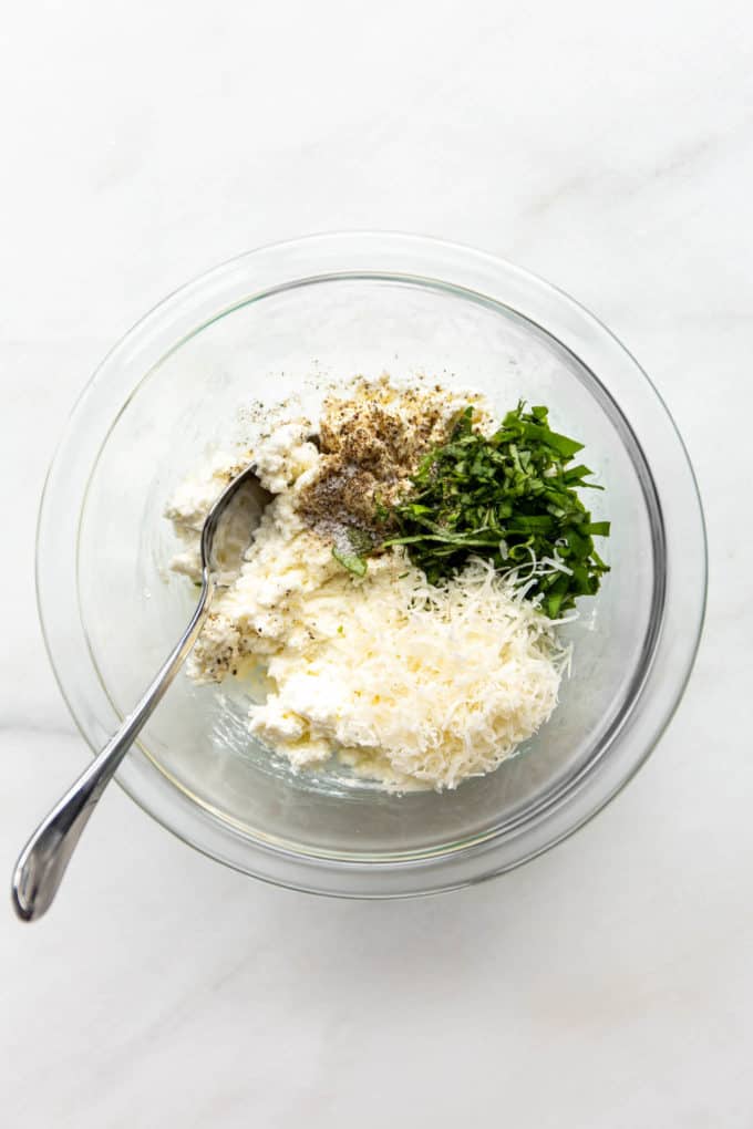 Ricotta, Parmesan and basil in a clear mixing bowl