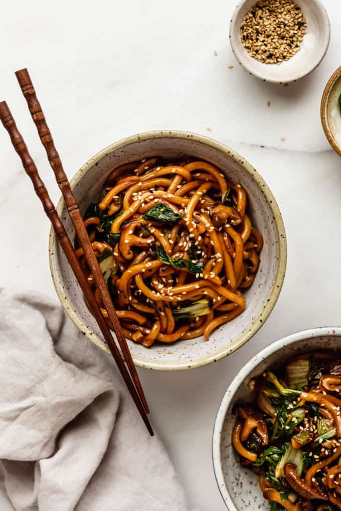 two bowls of yaki udon noodles on a marble board with a napkin on the side