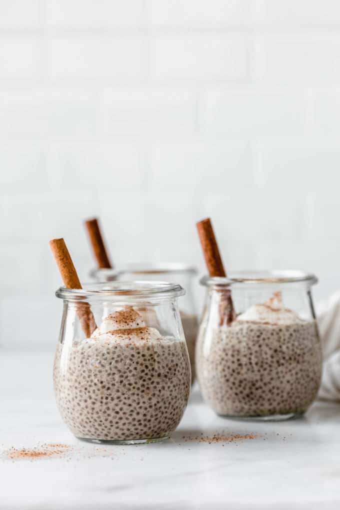 Eggnog chia pudding in a jar topped with yogurt and a cinnamon stick