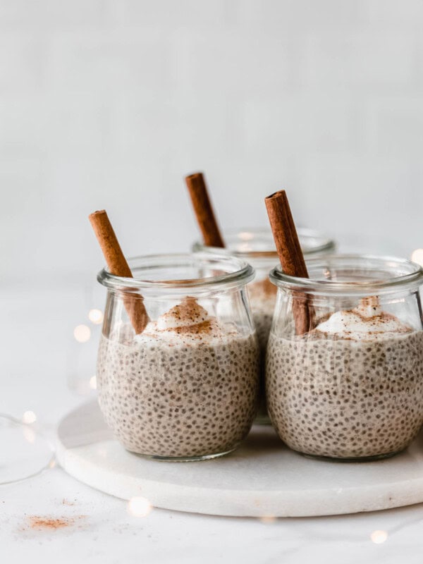 jars of eggnog chia pudding with a cinnamon stick in them