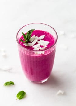 a dragon fruit smoothie in a glass topped with coconut flakes