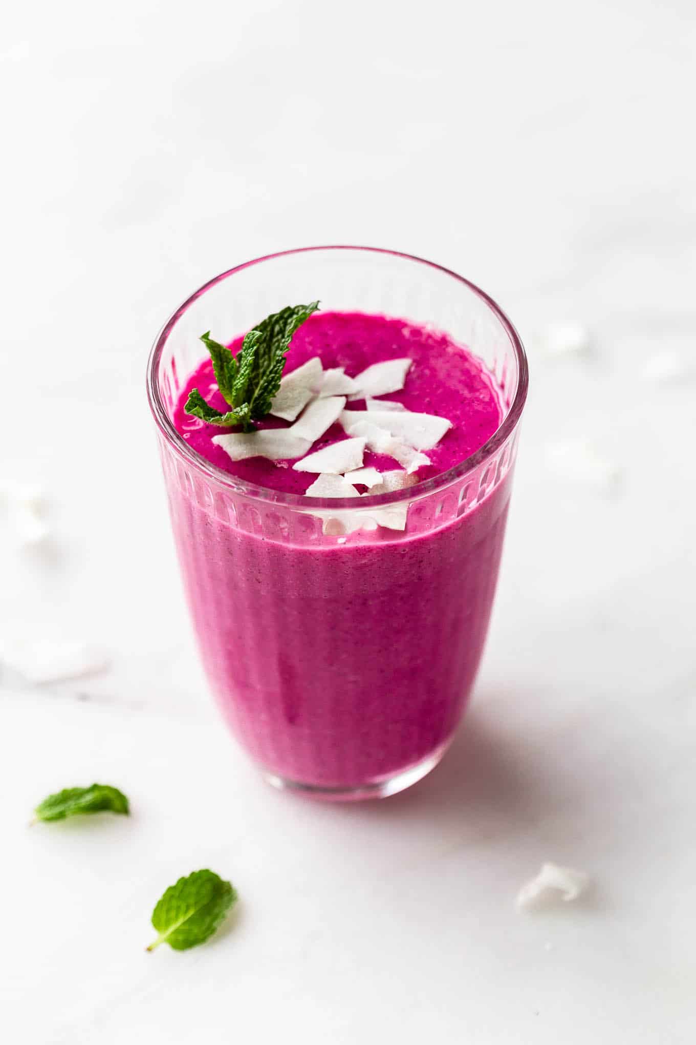 a dragon fruit smoothie in a glass topped with coconut flakes