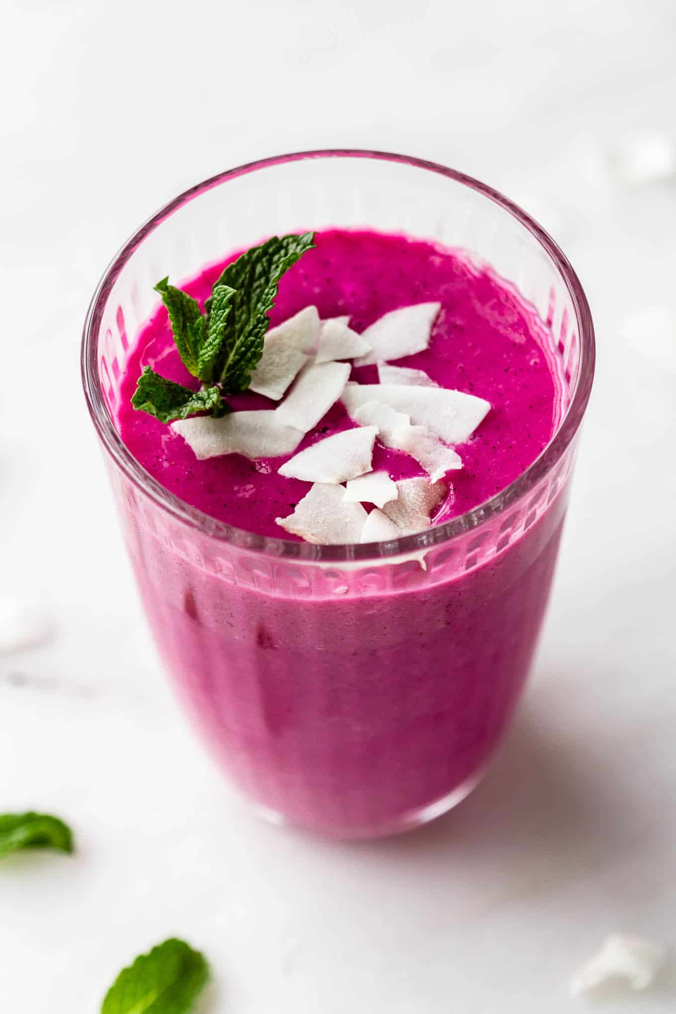 a dragon fruit smoothie topped with coconut and mint