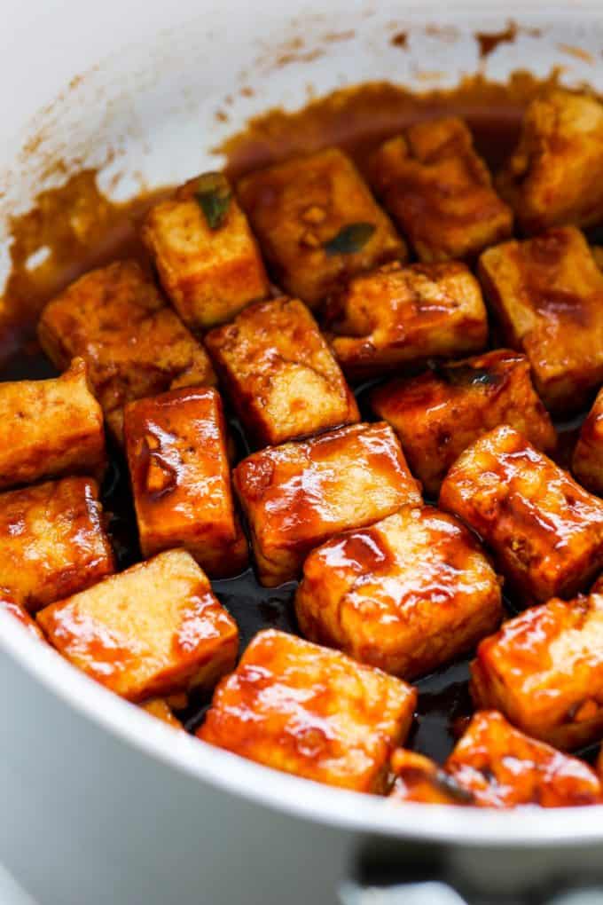 a close up of cubed tofu in sesame sauce in a pan