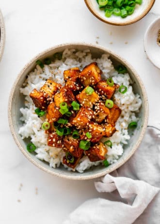sesame tofu and rice in a bowl with a grey napkin on the side