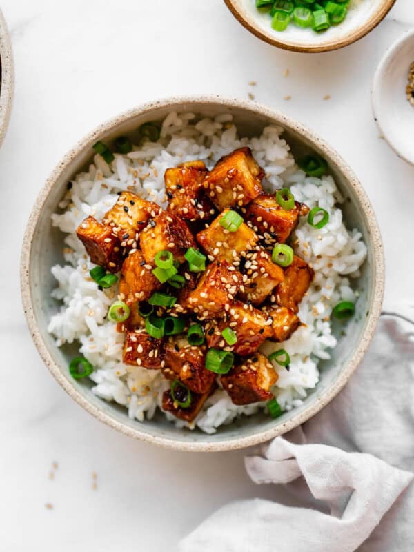 sesame tofu and rice in a bowl with a grey napkin on the side