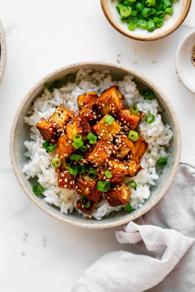 sesame tofu and rice in a bowl with a grey napkin on the side