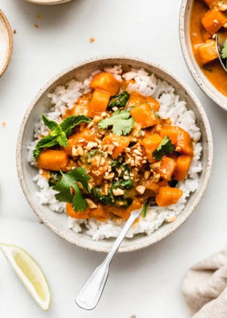 a bowl of sweet potato curry over rice with crushed peanuts on top