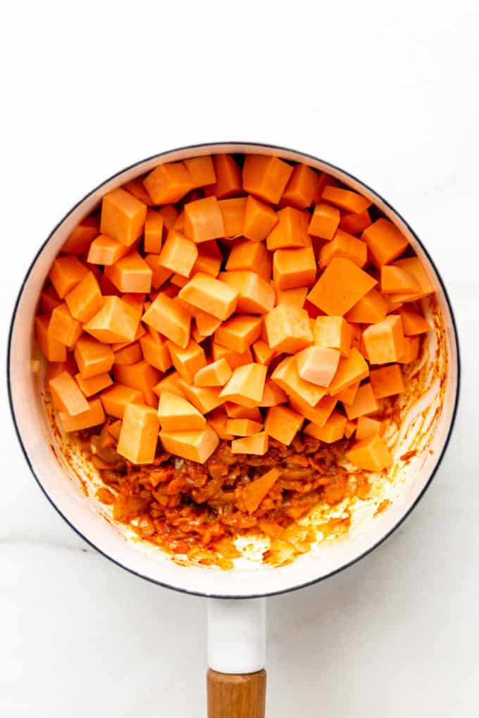 cubed sweet potatoes with curry paste in a white pot
