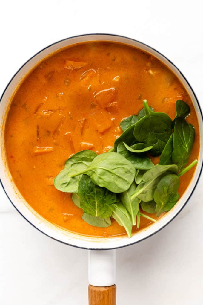 cooked sweet potato curry with fresh spinach in a pot