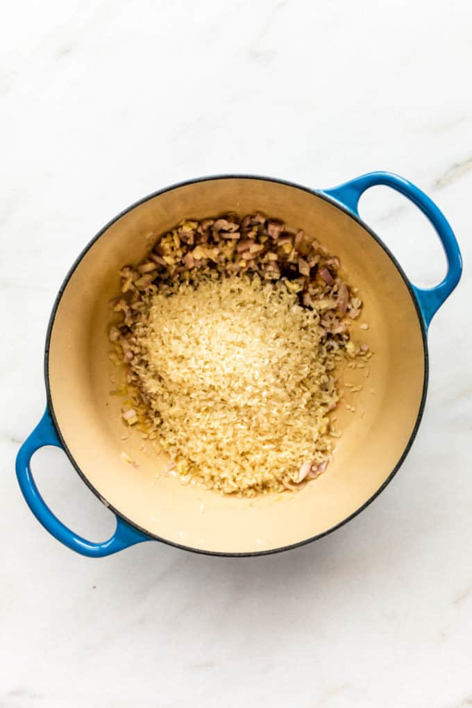 arborio rice in a pot with shallots and garlic