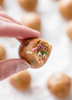 a hand holding a protein ball with a bite taken out of it