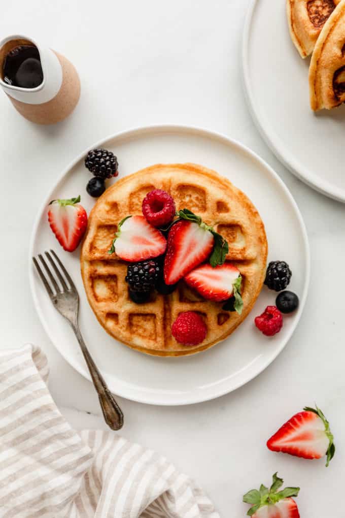 An almond flour waffle topped with berries on a white plate