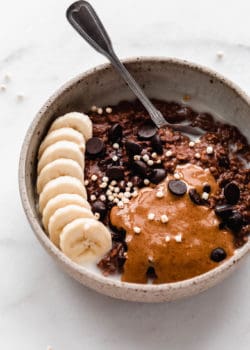 a bowl of chocolate oatmeal topped with bananas with a spoon in it