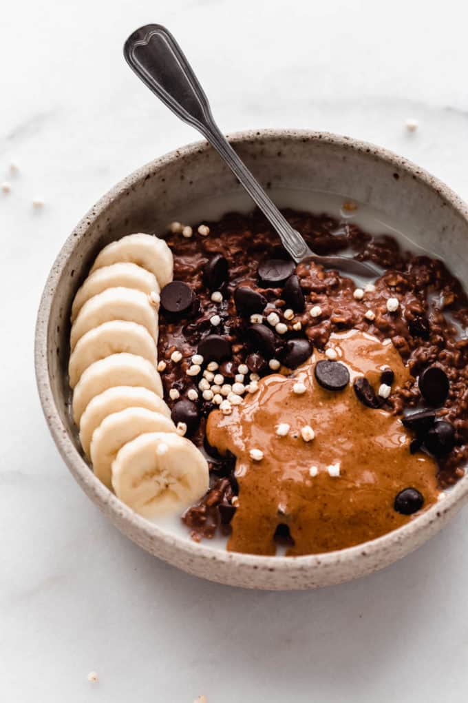 a bowl of chocolate oatmeal topped with bananas with a spoon in it
