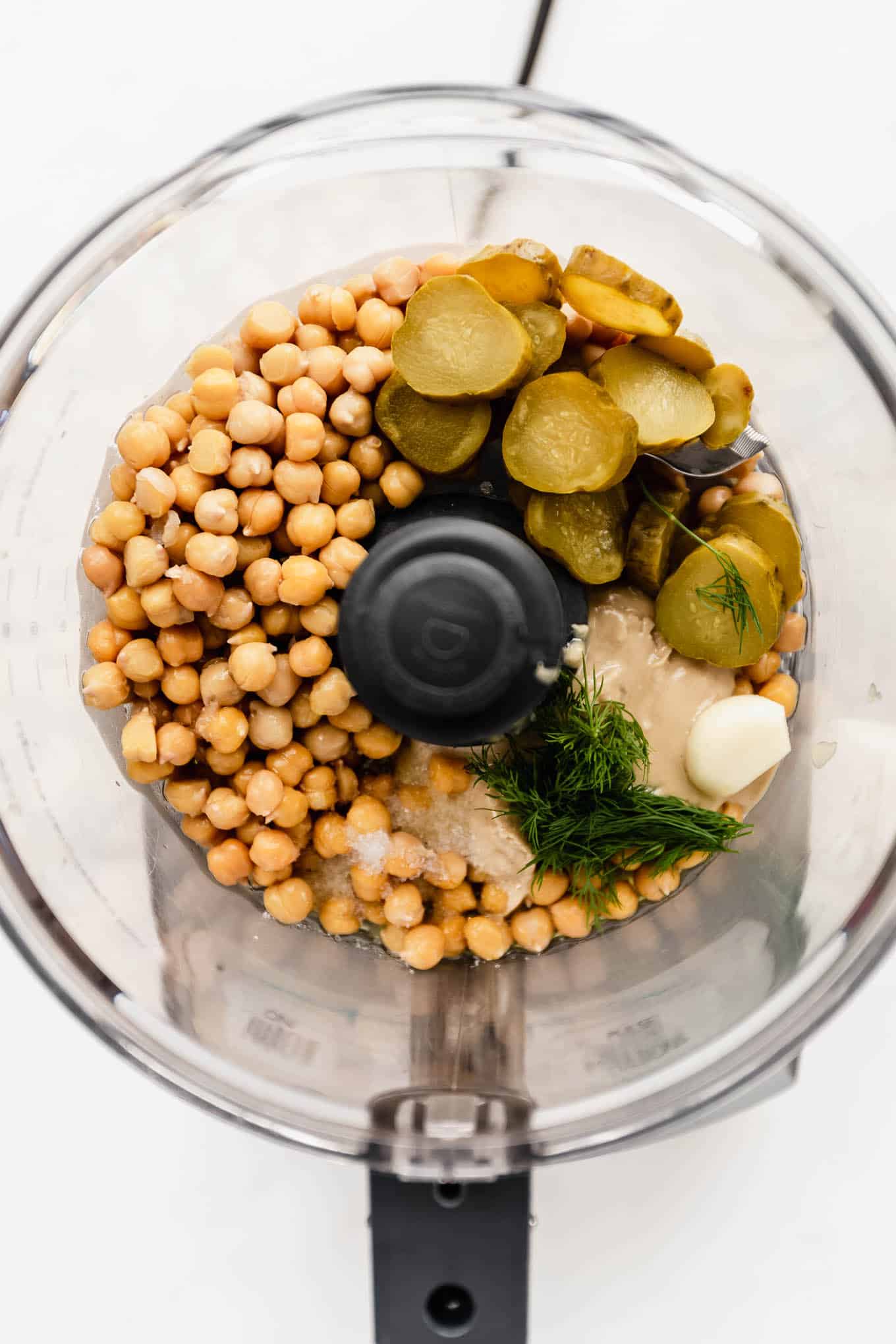 a food processor with chickpeas and pickles in it