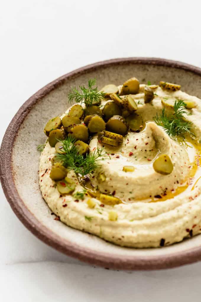 dill pickle hummus topped with chopped pickles and dill