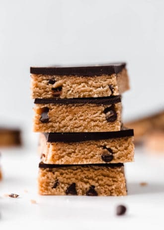 a stack of cookie dough bars topped with dark chocolate