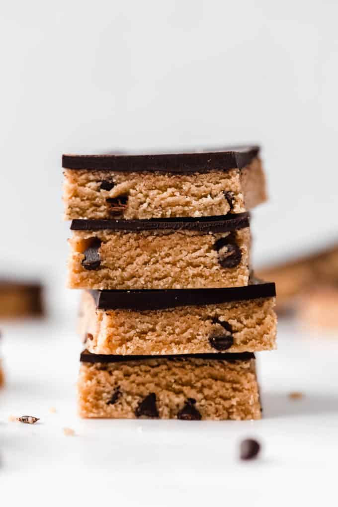 a stack of cookie dough bars topped with dark chocolate