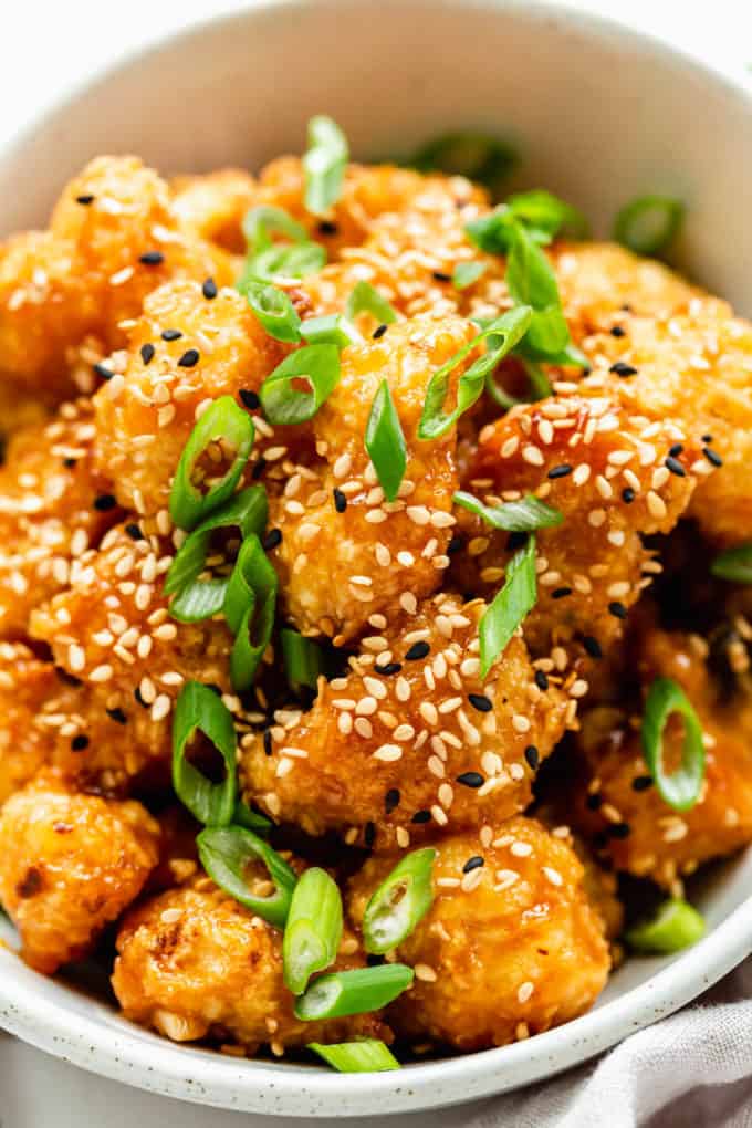 orange cauliflower topped with sesame seeds and scallions