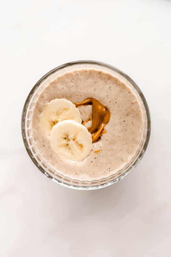 a top down view of a banana peanut butter smoothie with sliced banana on top