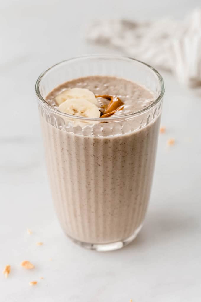 Peanut butter banana smoothie in a glass topped with banana