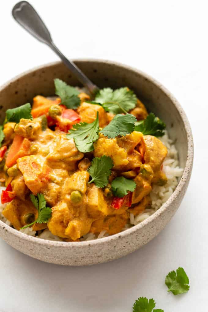 a bowl of vegetable korma topped with cilantro