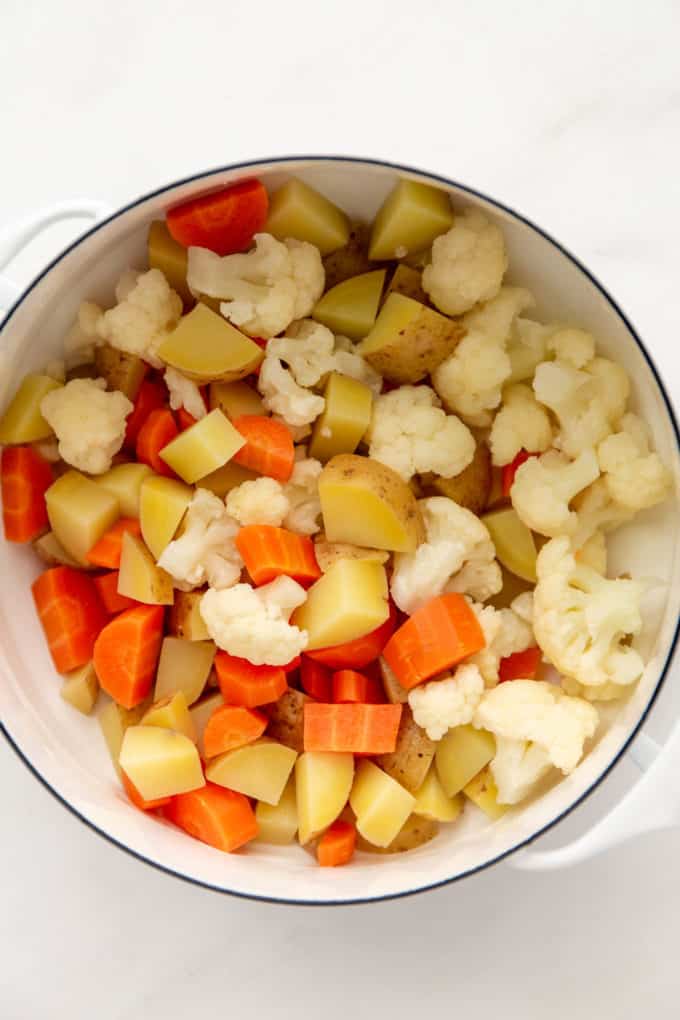 steamed potatoes, carrots and cauliflower in a white pot