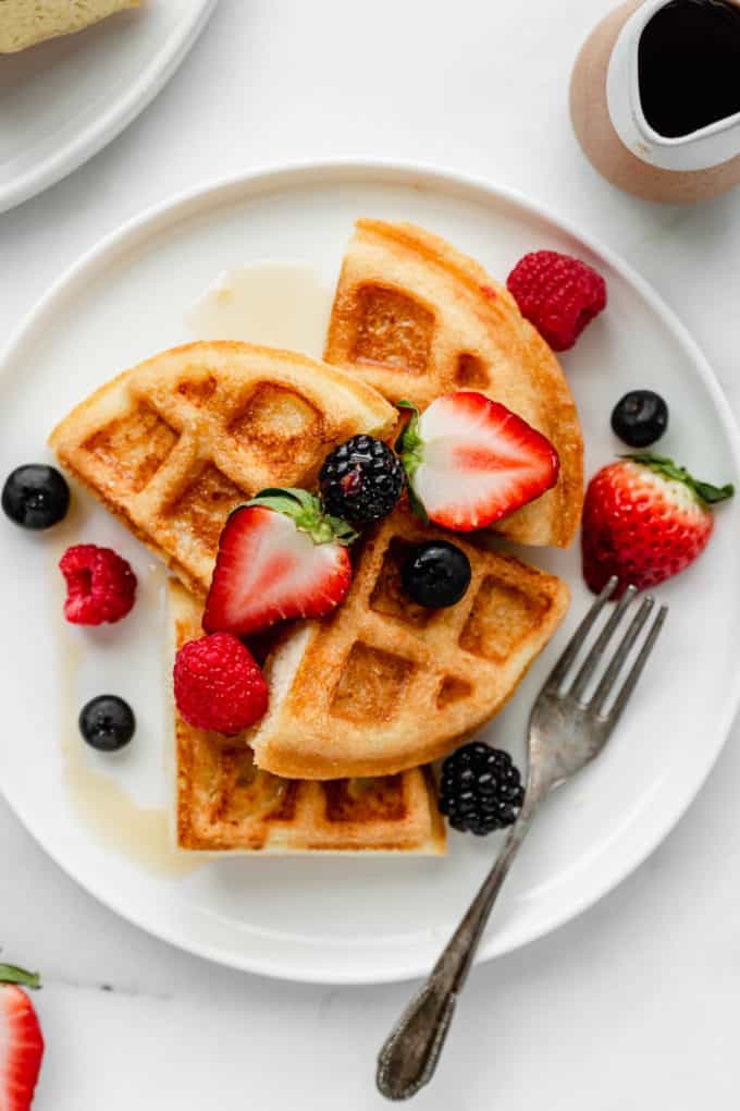 Almond flour waffles on a plate with maple syrup on the side