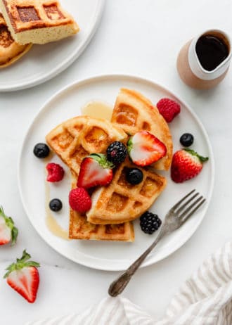 A plate of almond flour waffles topped with strawberries, blackberries, blueberries and raspberries