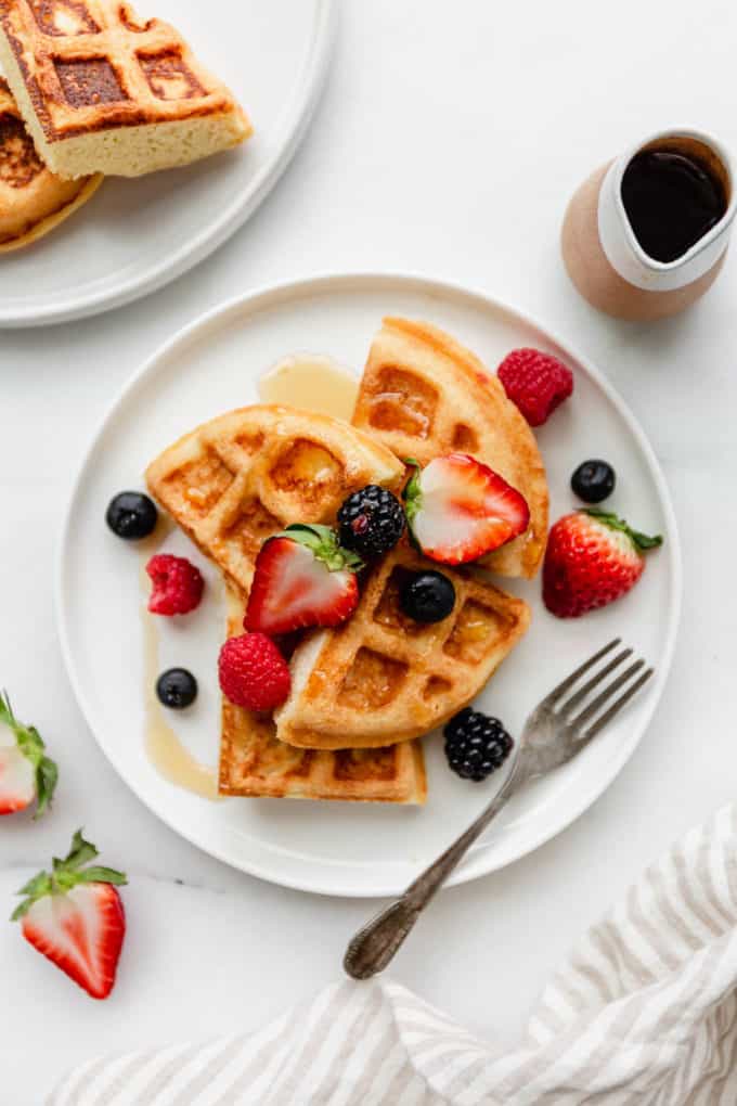 A plate of almond flour waffles topped with strawberries, blackberries, blueberries and raspberries