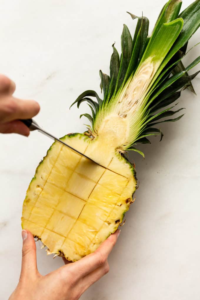 a knife cutting slits in a pineapple