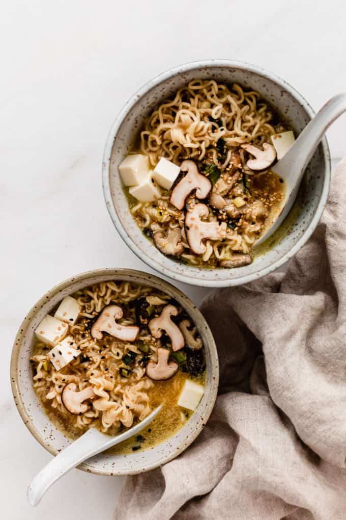 two bowls of miso ramen with spoons and a napkin on the side