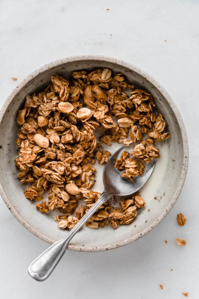a bowl of peanut butter granola with milk and a spoon in it
