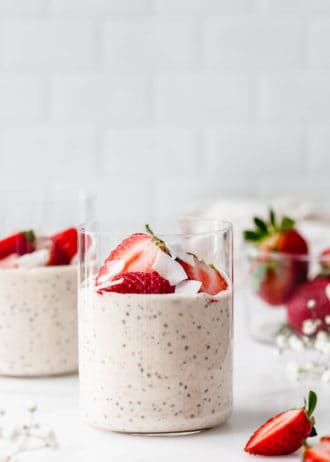 two cups of protein overnight oats with strawberries and coconut flakes