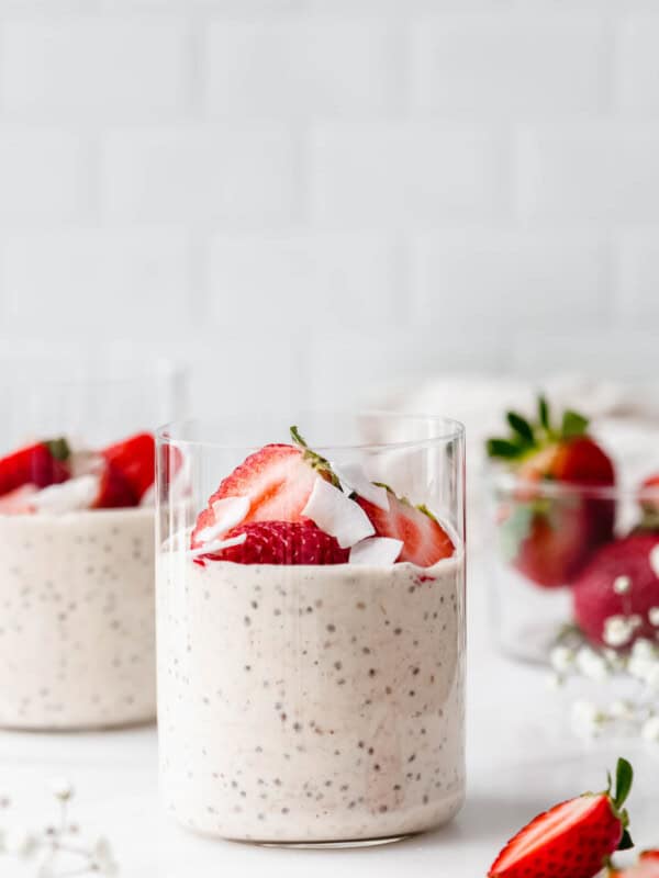 two cups of protein overnight oats with strawberries and coconut flakes