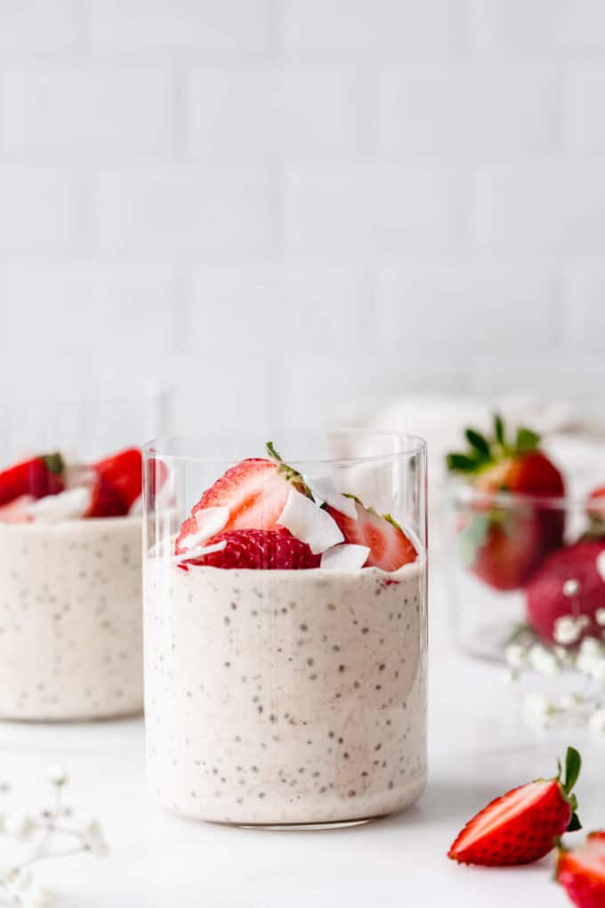 two cups of protein overnight oats with strawberries and coconut flakes