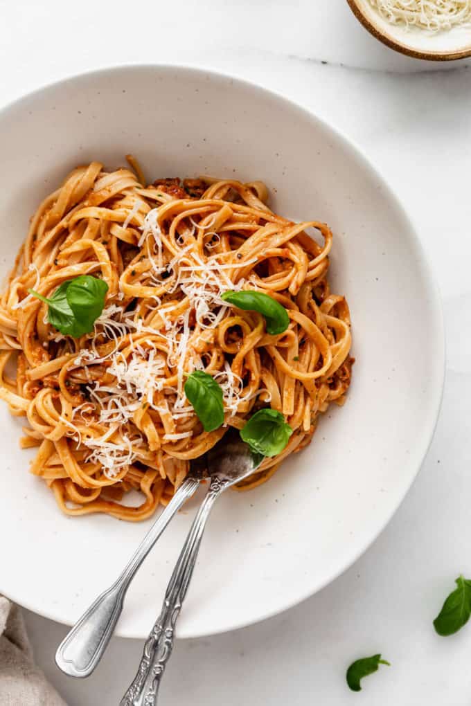 A bowl of red pesto pasta topped with parmesan cheese