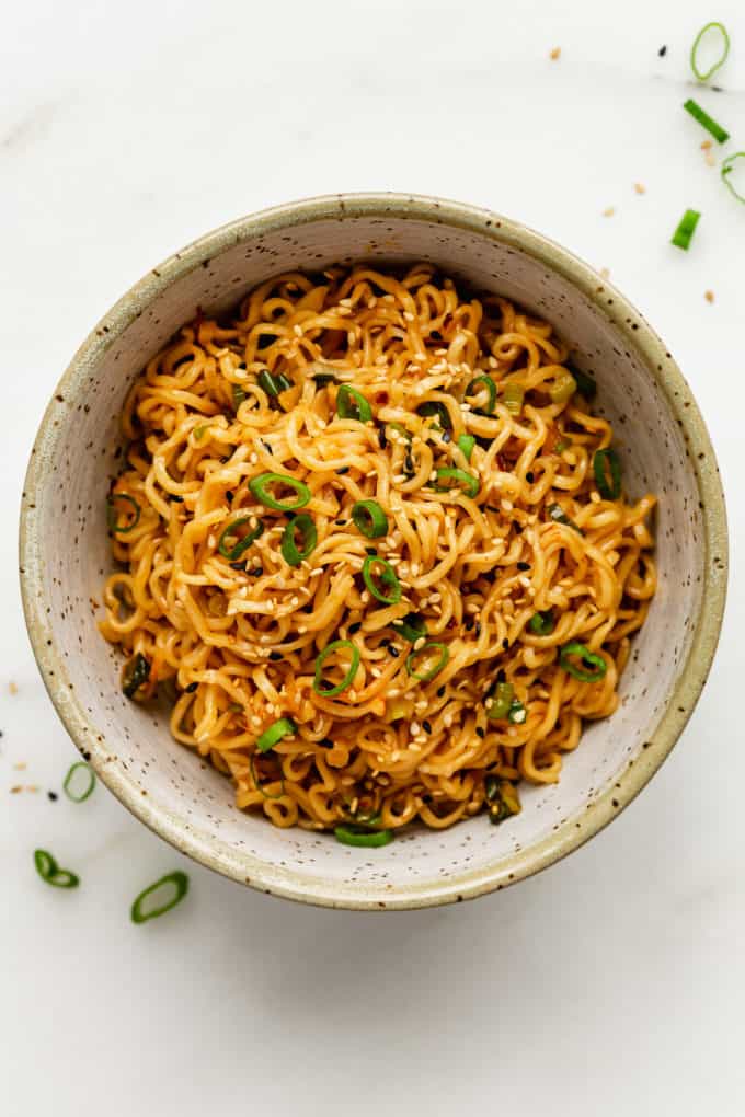 a bowl of spicy noodle topped with green onions